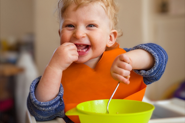 Toddler feeding himself and smiling